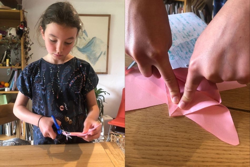 Flicka tillverkar en origamifjäril som är en kattleksak