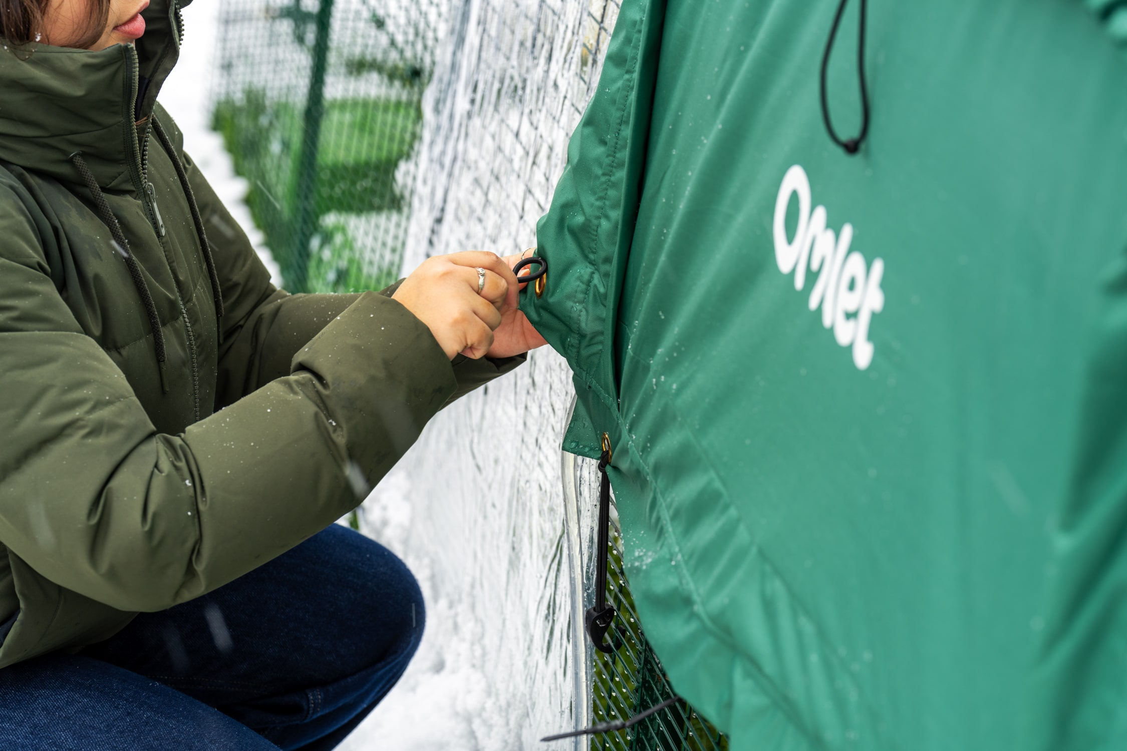 kvinna fäster ett extremvädersöverdrag på en Eglu Pro